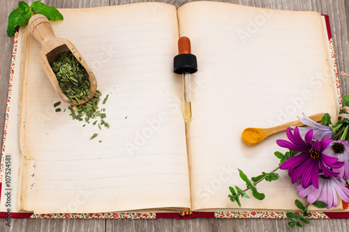 naturopathy concept with recipe book and medical herbs and flowe
