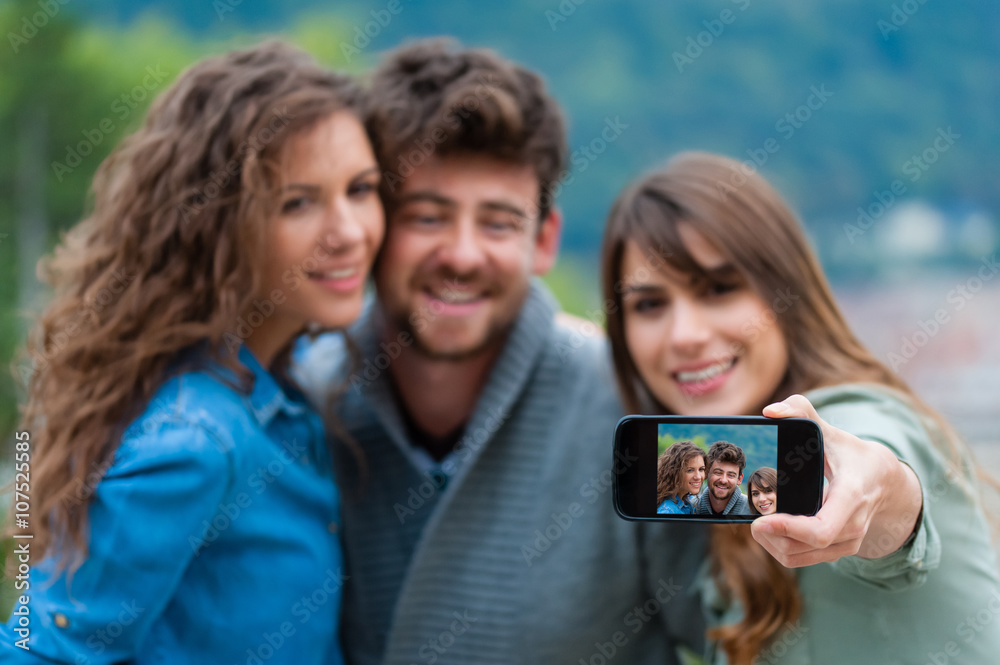 Friends taking selfportrait with mobile phone, outdoors. Friends taking selfportrait with mobile phone, outdoors.