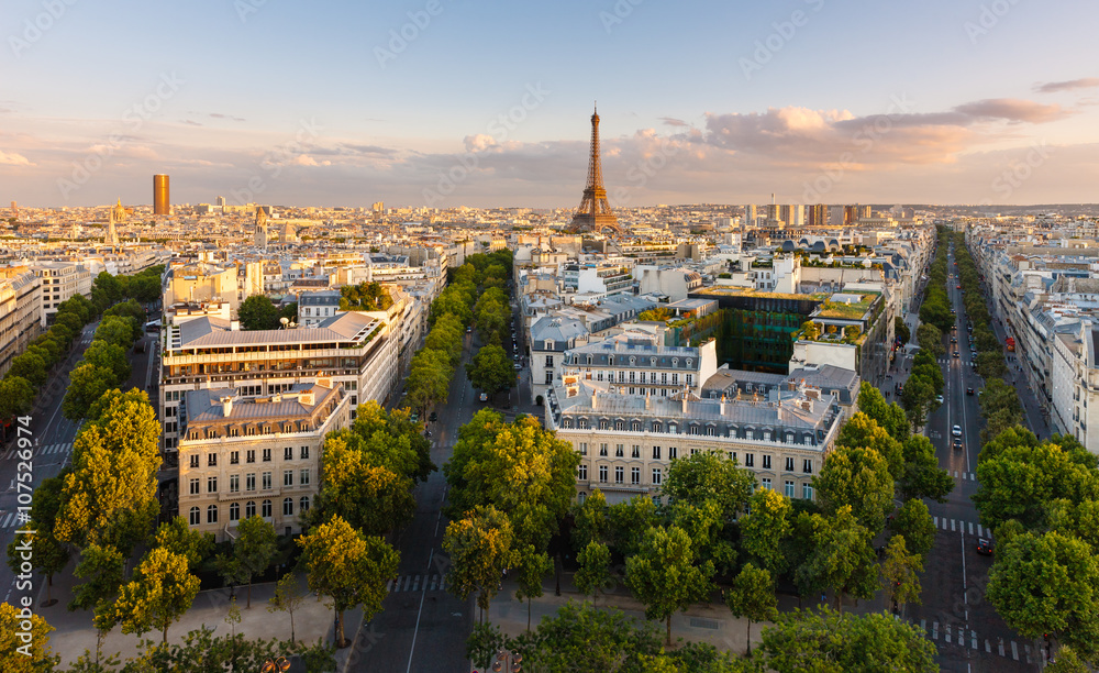Fototapeta premium Paryż z góry prezentujący dachy, Wieżę Eiffla, wysadzane drzewami aleje z haussmannowskimi budynkami oświetlonymi przez zachodzące słońce. Avenue Kleber, Avenue d'Iena i Avenue Marceau, 16. dzielnica