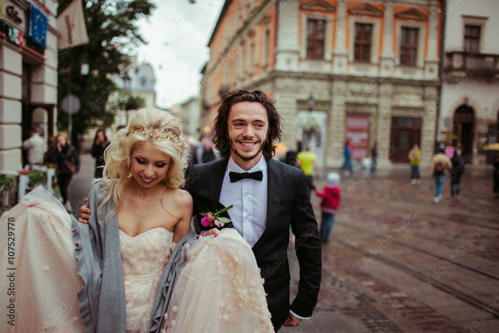 Happy newlywed couple walking in spring european street Happy newlywed couple walking in spring european street