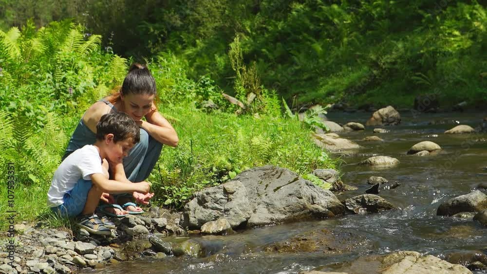 Mother with her son are sitting near a stream Mother with her son are sitting near a stream