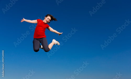 Teenage girl jumping outdoor against blue sky