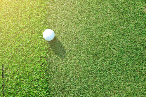 Golf ball sitting between apron fringe and green