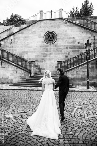 Romantic fairytale newlywed couple holding hands near old baroqu photo