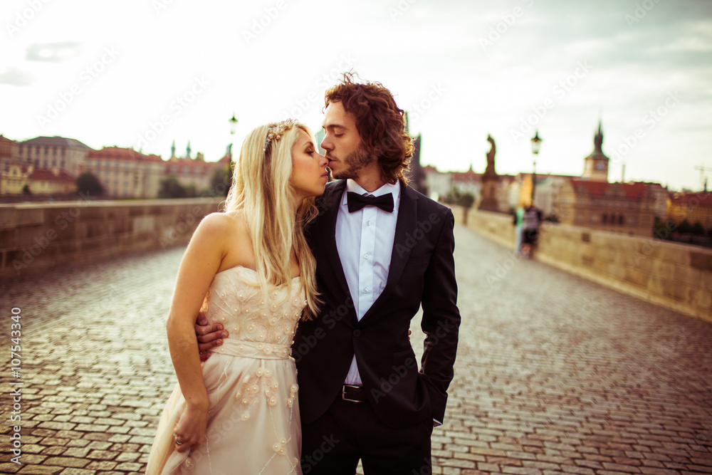 Romantic newlywed couple on honeymoon, kissing on bridge in Prag