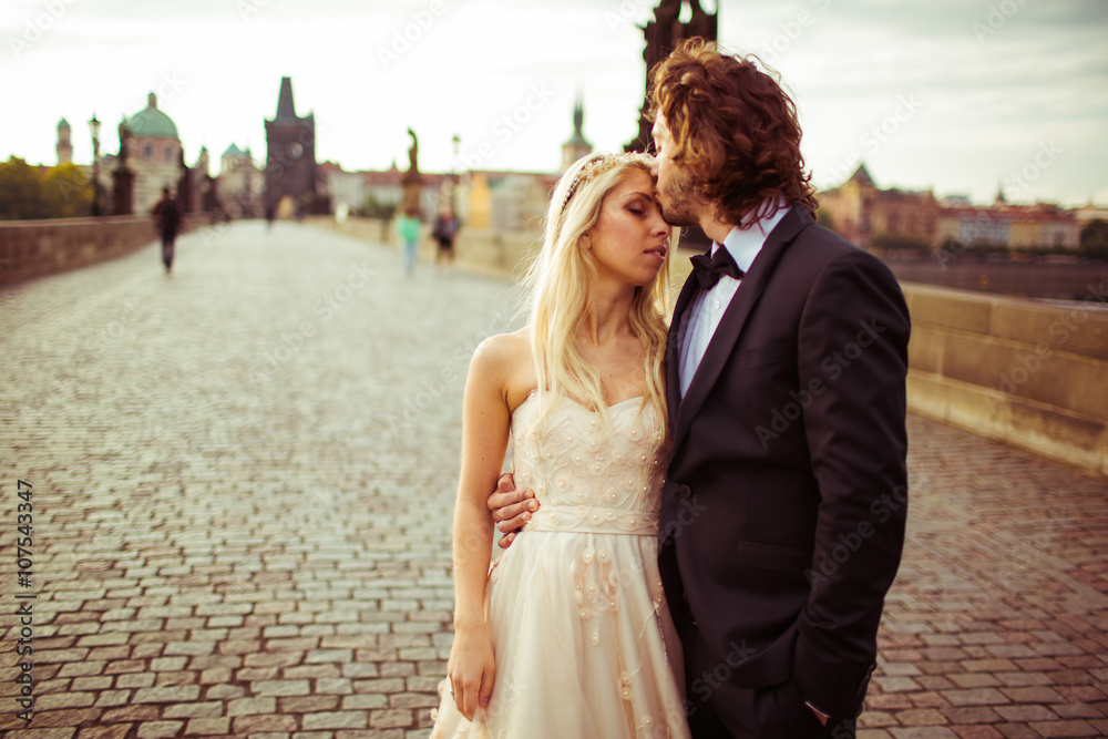 Naklejka premium Romantic newlywed couple on honeymoon, kissing on bridge in Prag