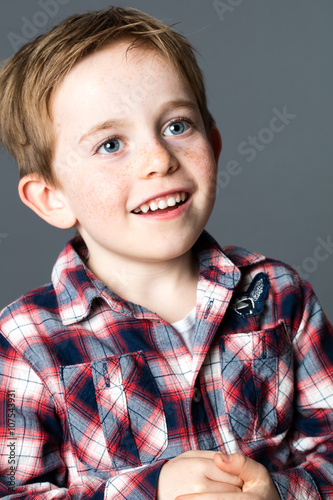 closeup portrait of a young male child with blue eyes and freckles laughing for sweet childhood,grey background studio.....