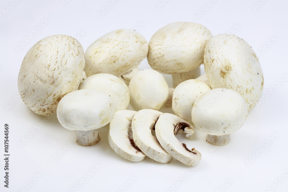 Bunch of button mushrooms with some slices, on white background.