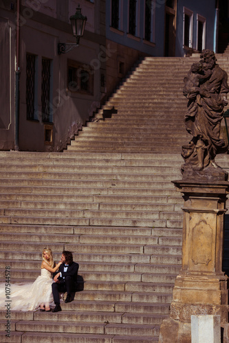 Sensual romantic newlywed couple sitting on old baroque stairs