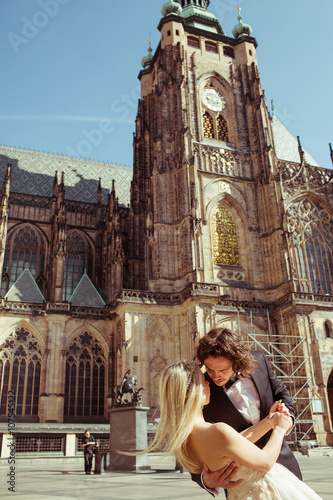 Newlywed couple dancing & hugging near baroque christian cathedr photo