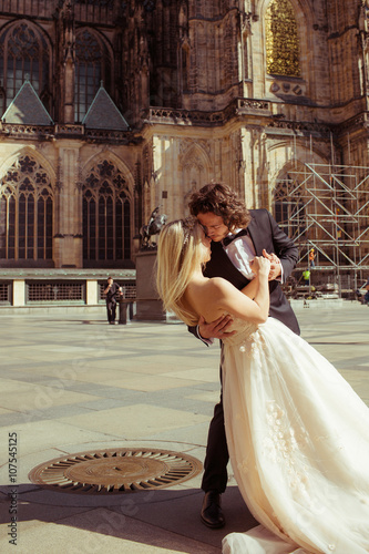 Newlywed couple dancing & hugging near baroque christian cathedr photo