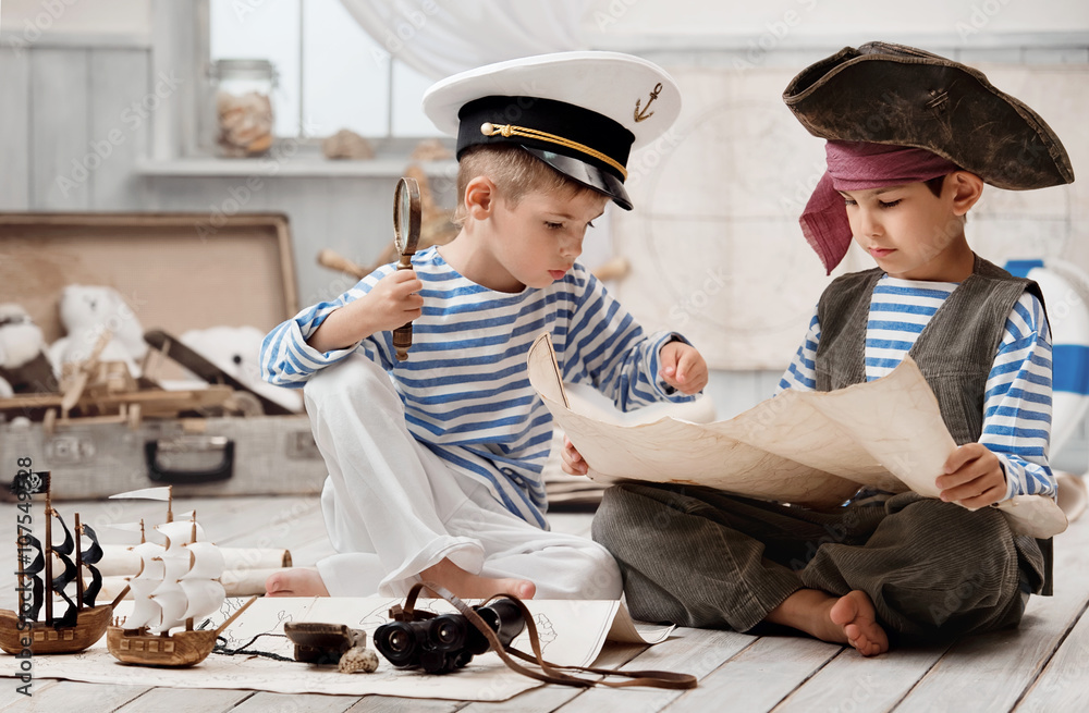 Fototapeta premium Chłopcy przebrani za kapitana piratów i czytający mapę podróży