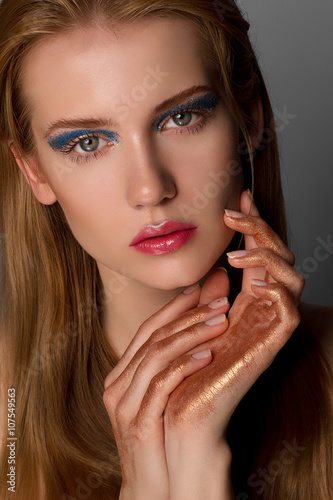 Beauty portrait of a beautiful blonde model with blue makeup on a gray background
