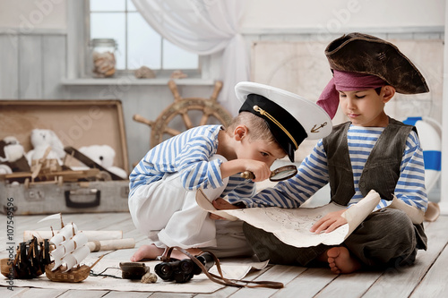 Fototapeta Chłopcy przebrani za piratów i czytają mapę podróży