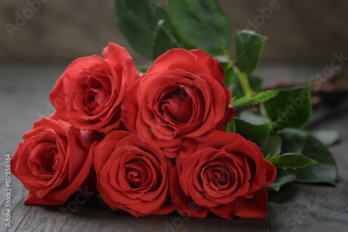 five red roses on wooden table  shallow focus