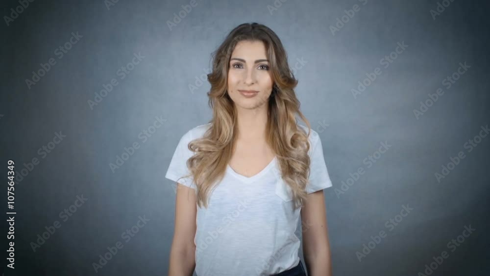 Portrait of a beautiful young woman showing thumbs up sign over grey background. Portrait of a beautiful young woman showing thumbs up sign over grey background.