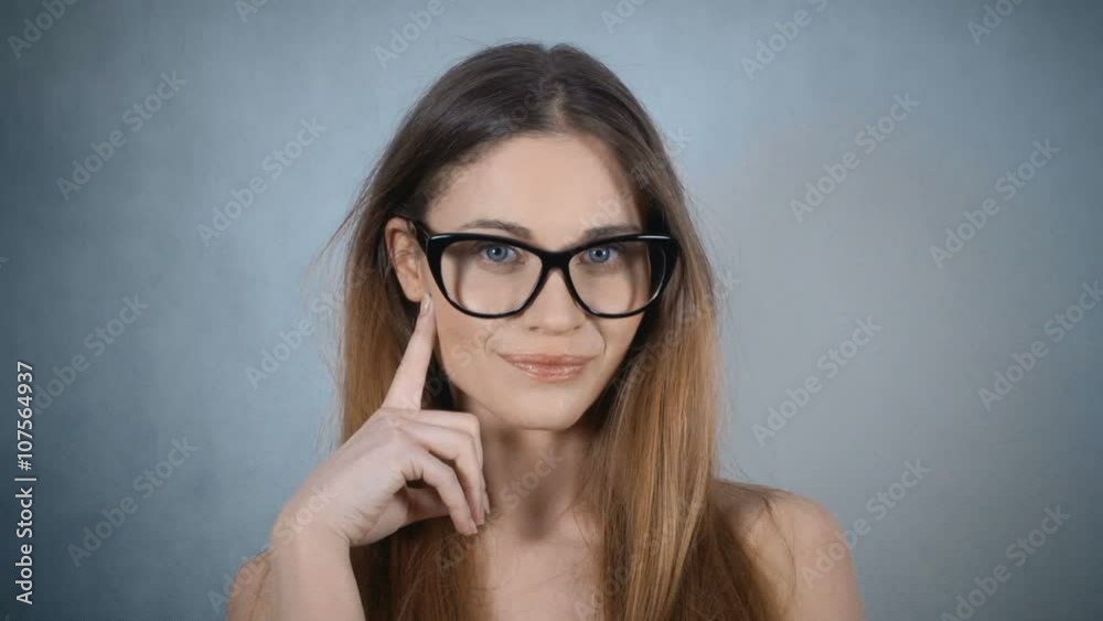 Happy toothy smiling young woman in glasses thinking on blue background with empty copy space. Studio shot. Happy toothy smiling young woman in glasses thinking on blue background with empty copy space. Studio shot.