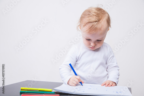 Baby girl drawing with colorful felt-tip pens white background