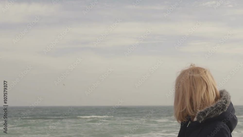 Young blond girl walks on the beach and smiling in the wind Young blond girl walks on the beach and smiling in the wind
