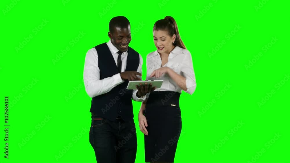 Two coworkers look at a laptop together. Green screen Two coworkers look at a laptop together. Green screen