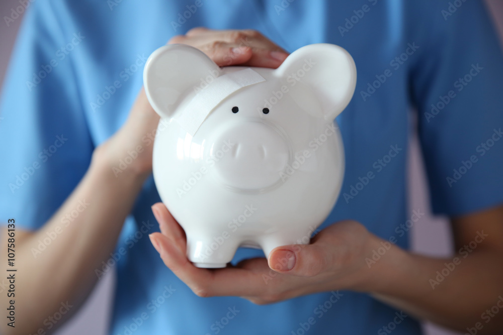 Woman holding in hands white piggy bank with patch Woman holding in hands white piggy bank with patch