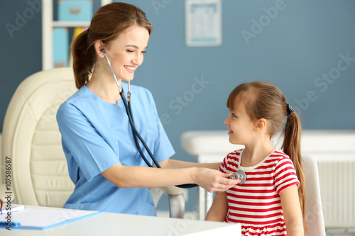 Doctor examining girl with stethoscope in the office