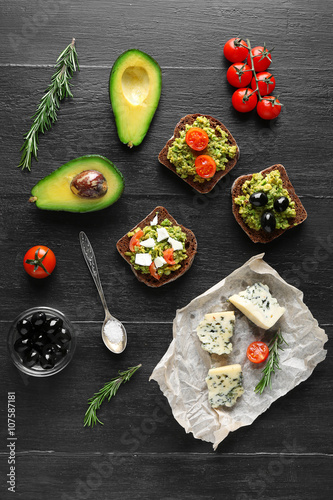 Avocado sandwiches with vegetables on dark wooden background