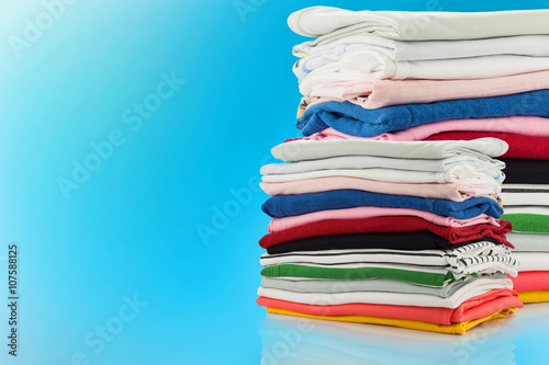 electric steam iron and Pile of colorful clothes isolated on blu