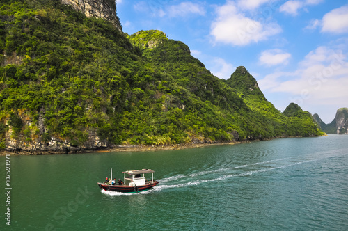 Small motor boat races among the islands of Halong Bay © alsem