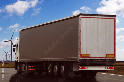 truck driving on the road against blue sky and wind wheels
