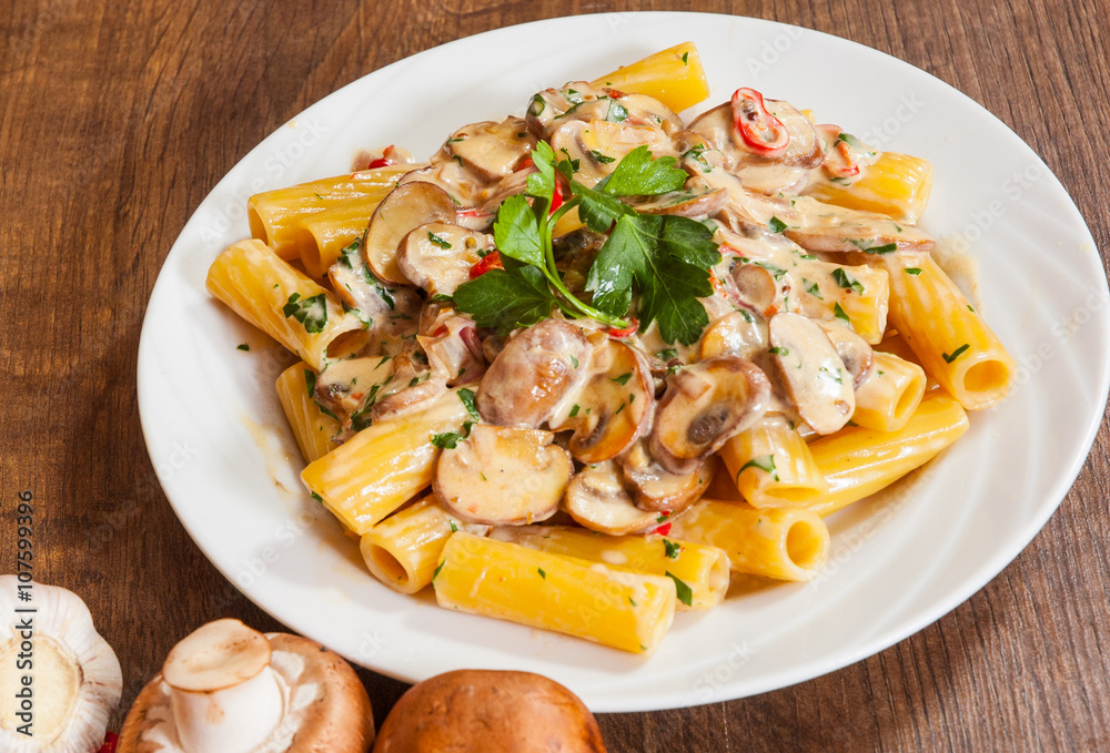 rigatoni pasta with mushroom sauce in a plate on wooden table