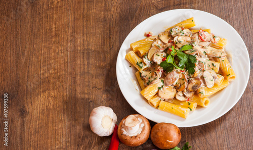 rigatoni pasta with mushroom sauce in a plate on wooden table