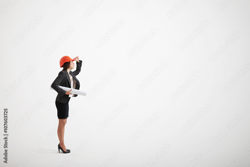 Woman in formal wear and construction helmet holding blueprints Woman in formal wear and construction helmet holding blueprints