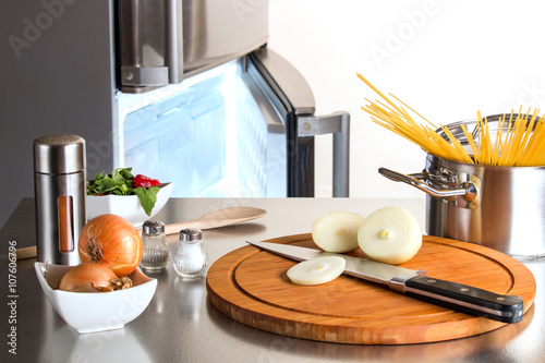 Zwiebeln, Spaghetti und Gewurze vor geöffnetem Tiefkühlfach eines Kühlschrankes
