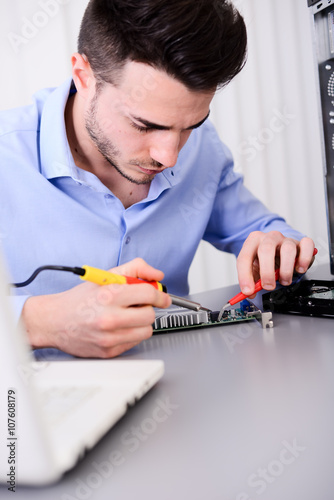 handsome young computer technician repairing desktop computer