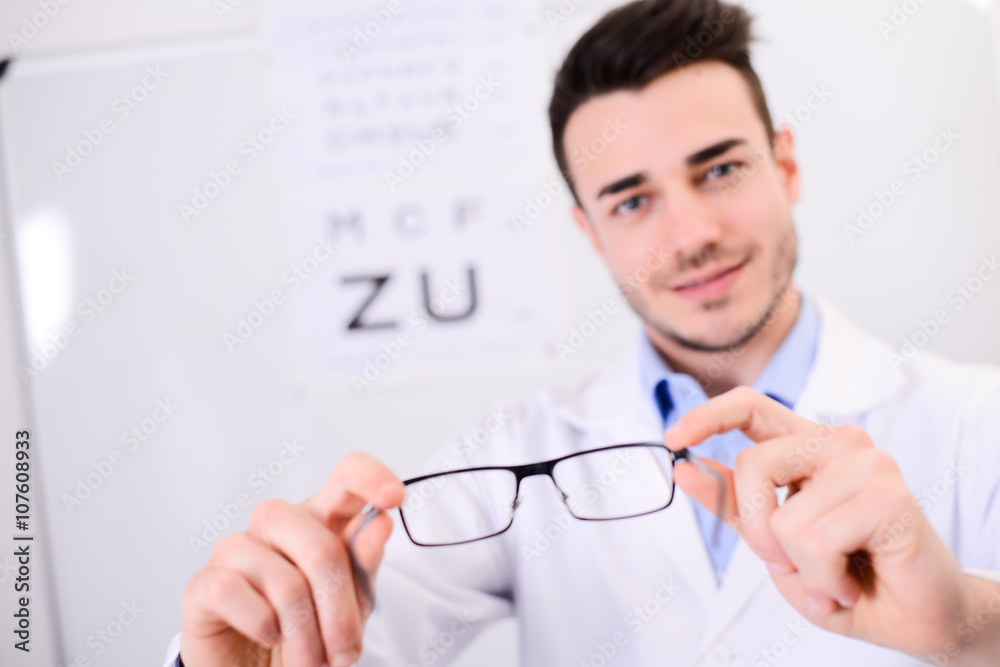 handsome young ophthalmologist handing over pair of eye glasses to patient handsome young ophthalmologist handing over pair of eye glasses to patient