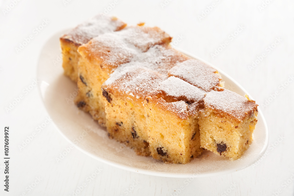 Homemade lemon cake with chocolate chips shot over white background from above. Full length view Homemade lemon cake with chocolate chips shot over white background from above. Full length view