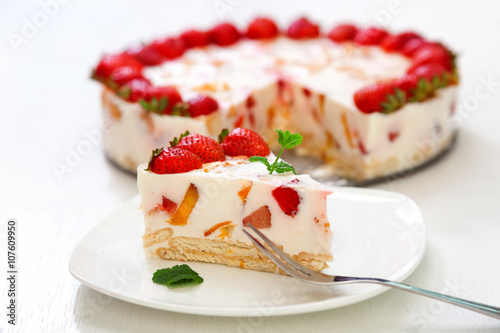 Cake with strawberries, gelly yogurt and cherries. Surface view. Isolated on white background. One piece in a white plate