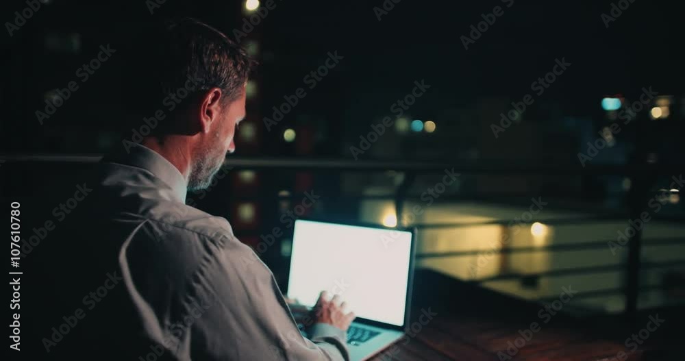 Mature man sitting on balcony and working on laptop