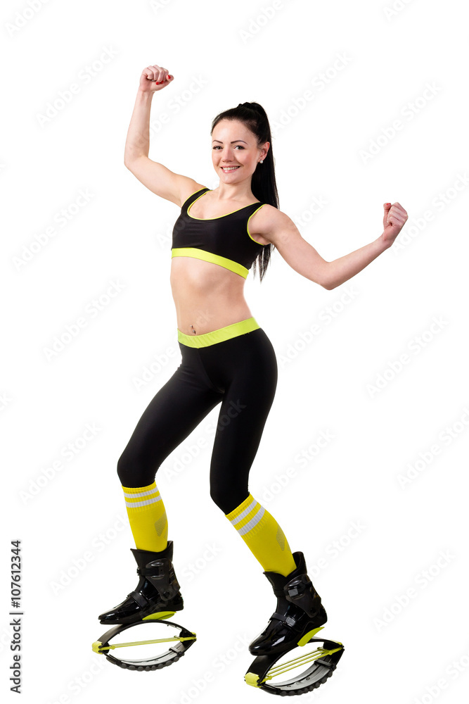 Smiling brunette girl in kangoo jumps shoes showing a muscles on