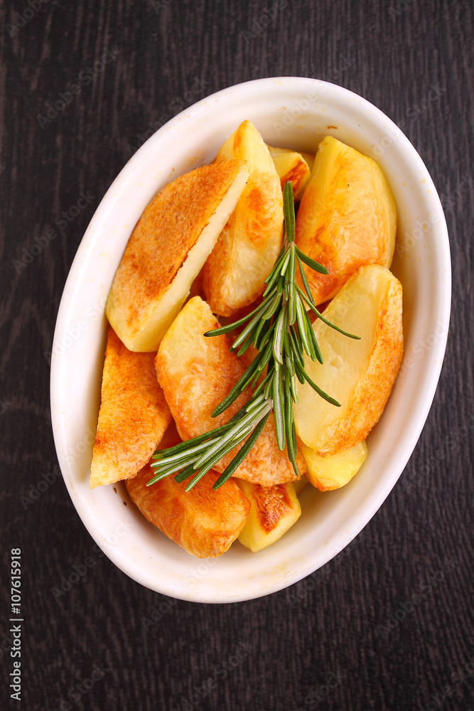 baked potatoes with spices in white bowl on a black background baked potatoes with spices in white bowl on a black background