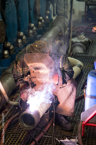 Welder during the repair welding of the pipeline in the engine room of the ship