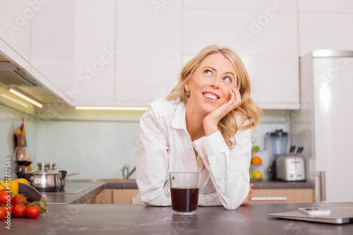 Woman in the kitchen with coffee daydreaming