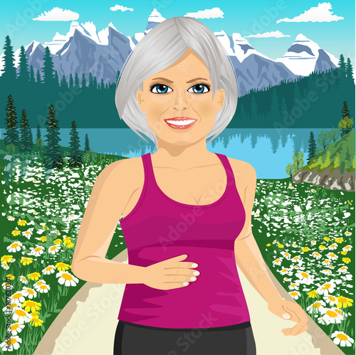 Senior woman jogging among beautiful mountains and field of daisy flowers
