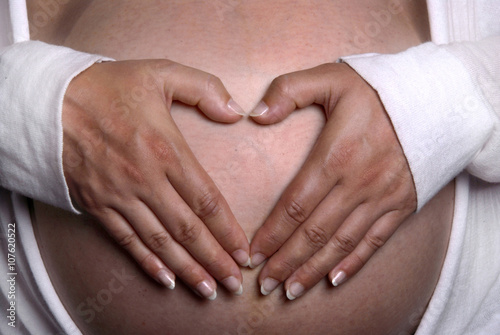 zwangere vrouw houdt beide handen in hartvorm op haar buik photo