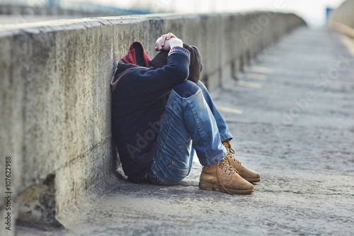 young homeless boy sleeping on the bridge photo