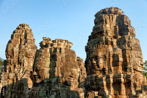 Dramatic view at sunset of one of the many large stone carved faces of Bayon Temple in Angkor Thom, Angkor district, Siem Reap, Cambodia