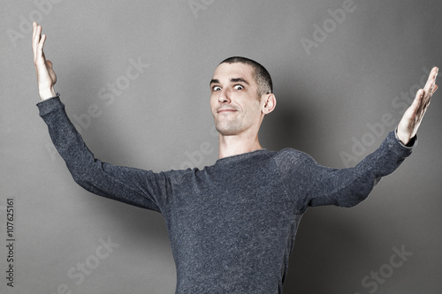 Bilde på lerret exaggeration concept -  expressive young man with eyes wide open opening his arm