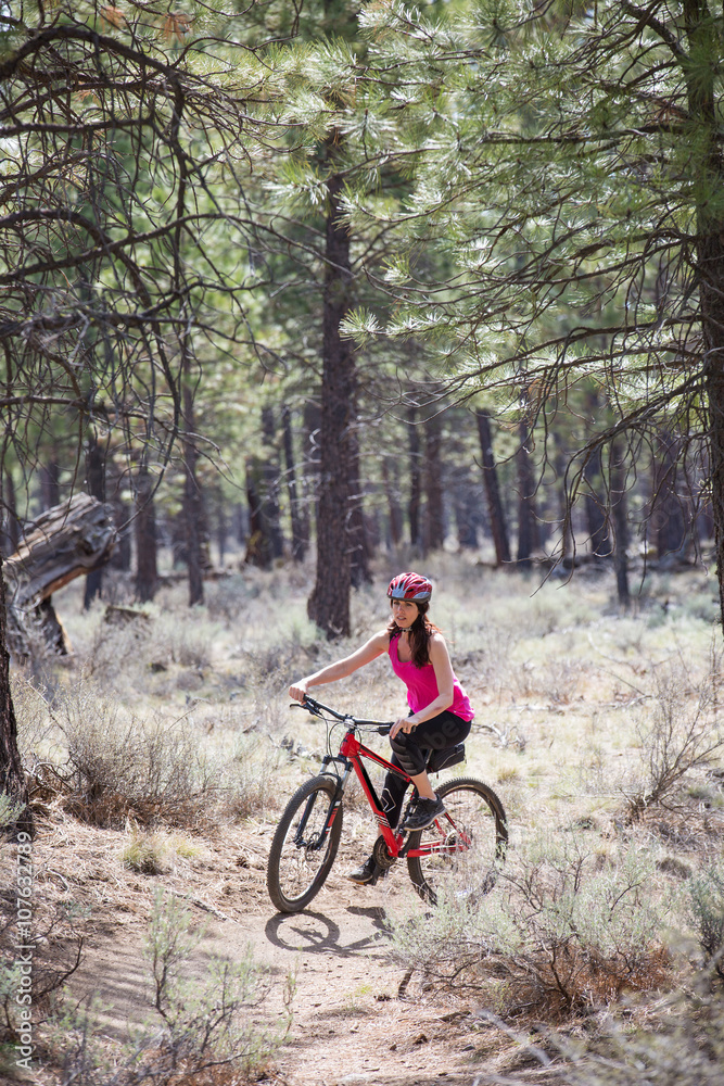 Woman riding mountain bike on trail in forest Woman riding mountain bike on trail in forest