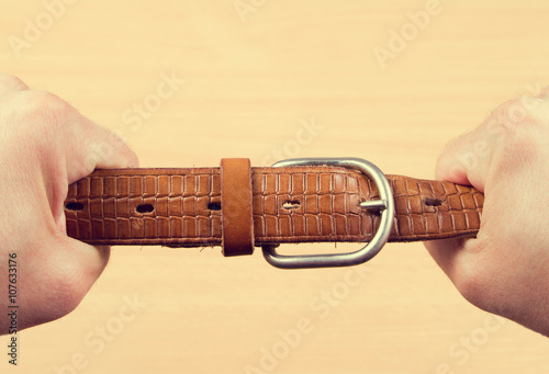 Two hands pulling a leather belt photo